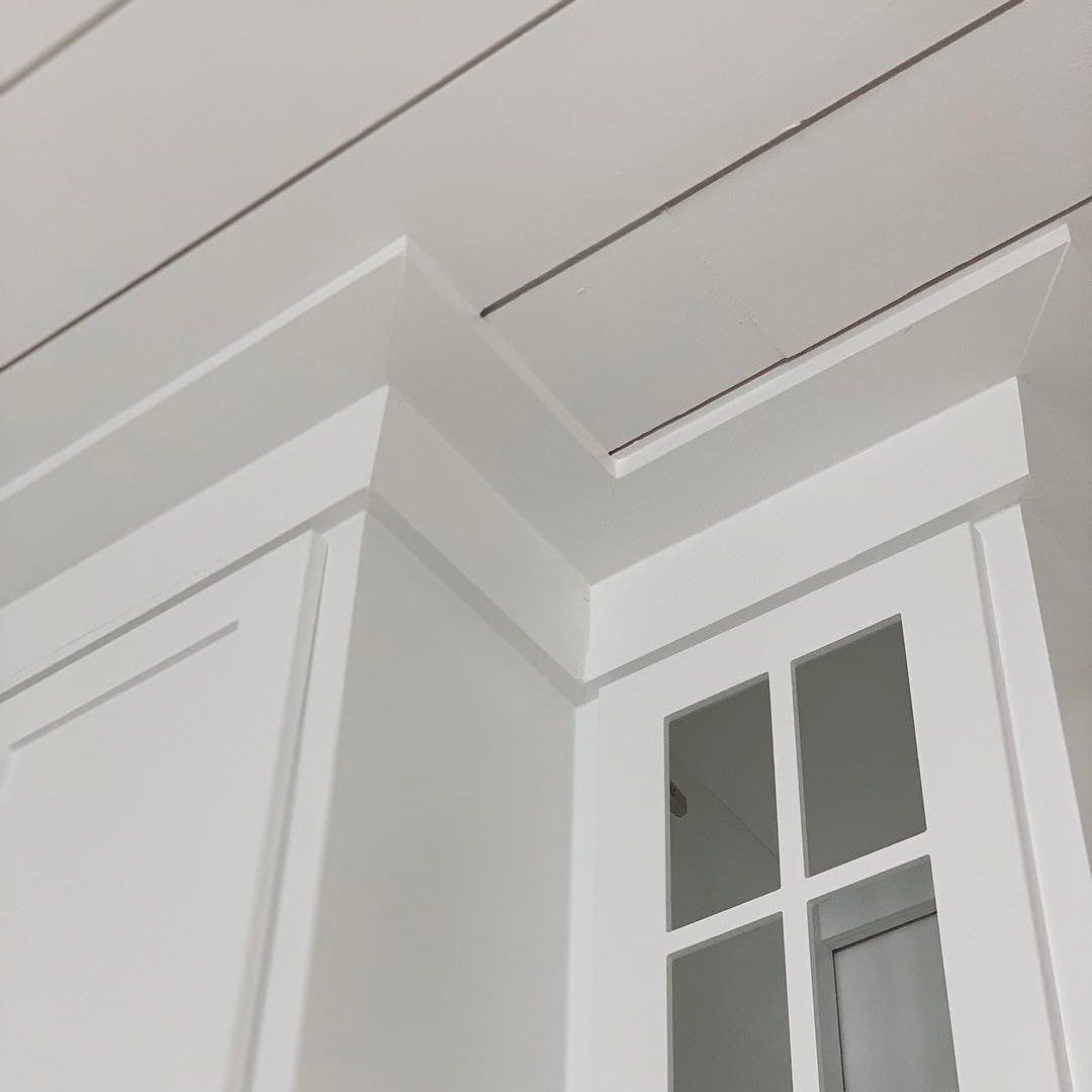 A white cabinet corner features a glass-paneled door. The ceiling above has clean lines, creating a bright, modern interior space.