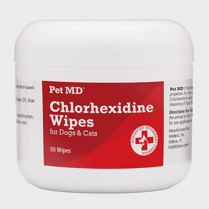 A round container holds chlorhexidine wipes for pets, indicating it cleanses dogs and cats. The container is labeled with product details and instructions.
