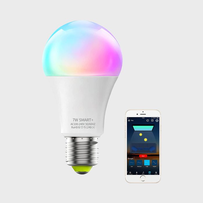 A smart LED bulb emits a colorful glow while a smartphone displays a control app for adjusting settings in a modern, minimalistic environment.