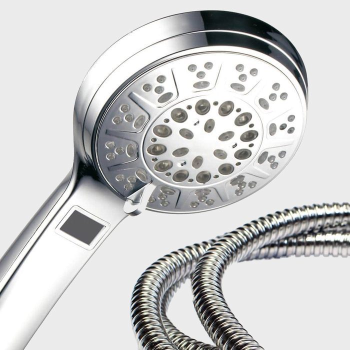 A chrome showerhead with multiple spray options hangs above a coiled metal hose, set against a simple gray background.