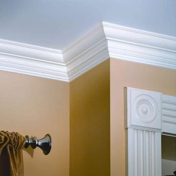 Crown molding meets a light brown wall corner, enhancing the room's elegance, alongside a decorative trim and curtain rod featuring a dark finish.