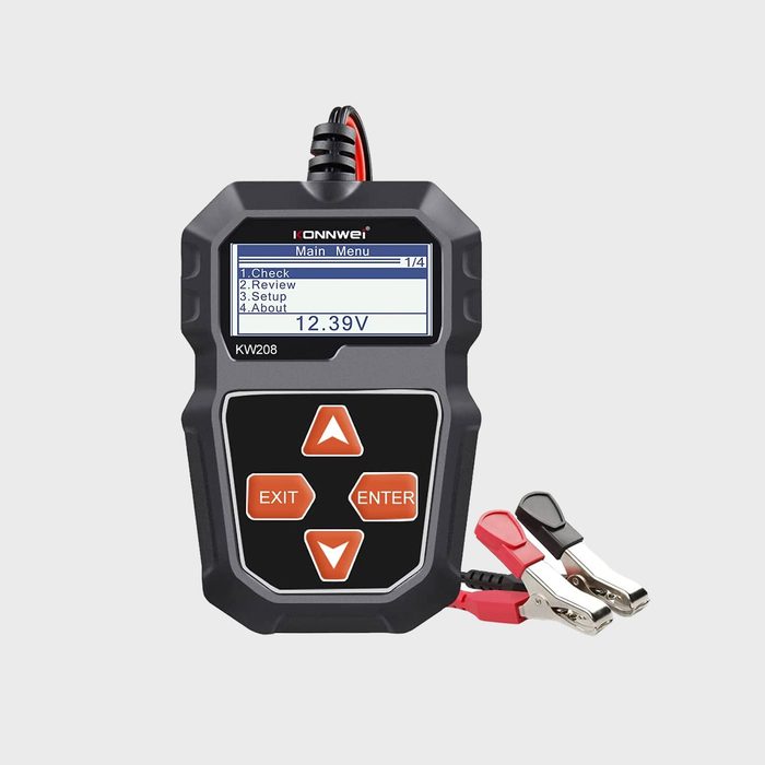 A voltage tester displays readings on a screen while connected to a battery via red and black clips, indicating functionality in electrical diagnostics.