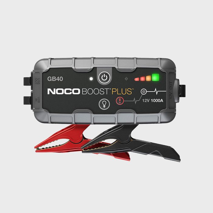 A portable jump starter features clamps and indicators, designed to boost car batteries. It rests against a neutral background, indicating usability and efficiency.