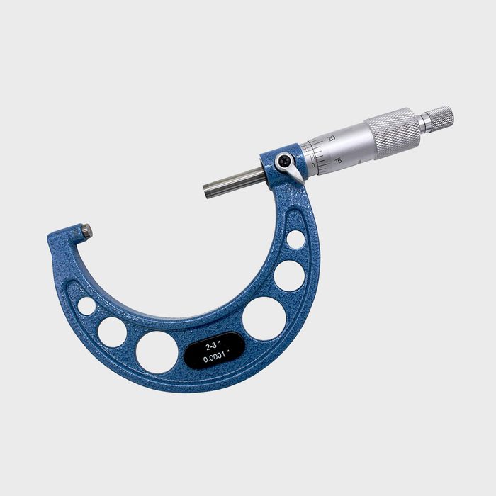 A blue micrometer measures small dimensions, adjusting the screw for precision in a neutral background, showcasing its calibration scale for accurate readings.