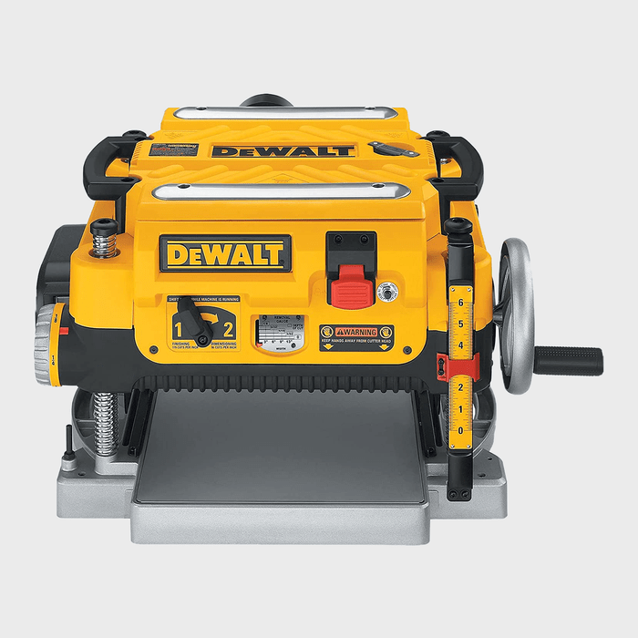 A yellow and black planer sits on a flat surface, ready for use, with various controls and gauges indicating operational settings.