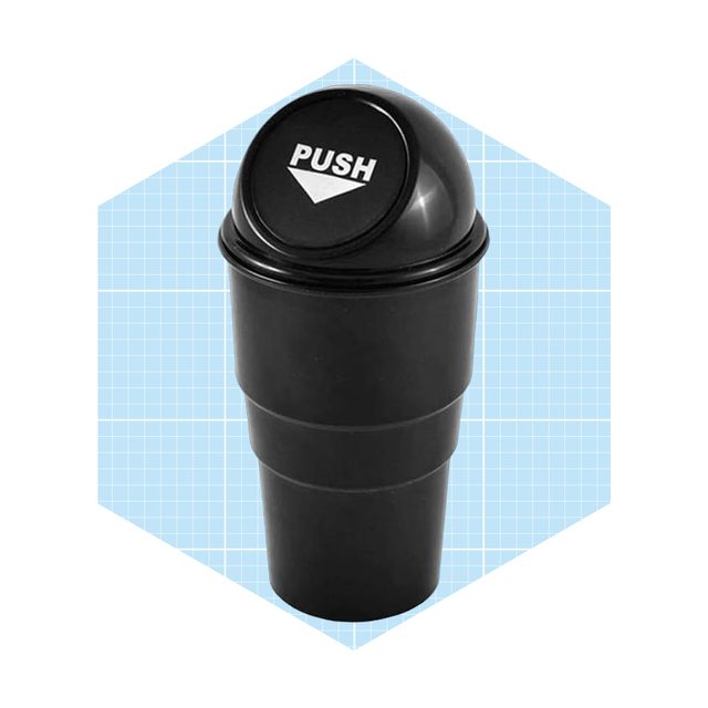 A black, two-part cylindrical container with a push-top lid sits against a light blue graph-patterned background, suggesting it's for disposing of waste.