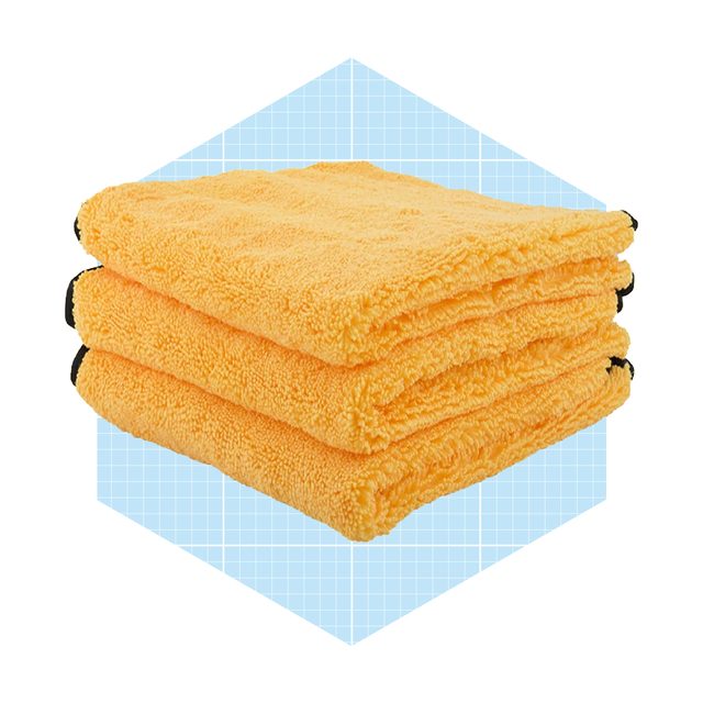 Three stacked, bright yellow microfiber towels sit on a light blue grid-patterned background, showcasing their soft texture and vibrant color.