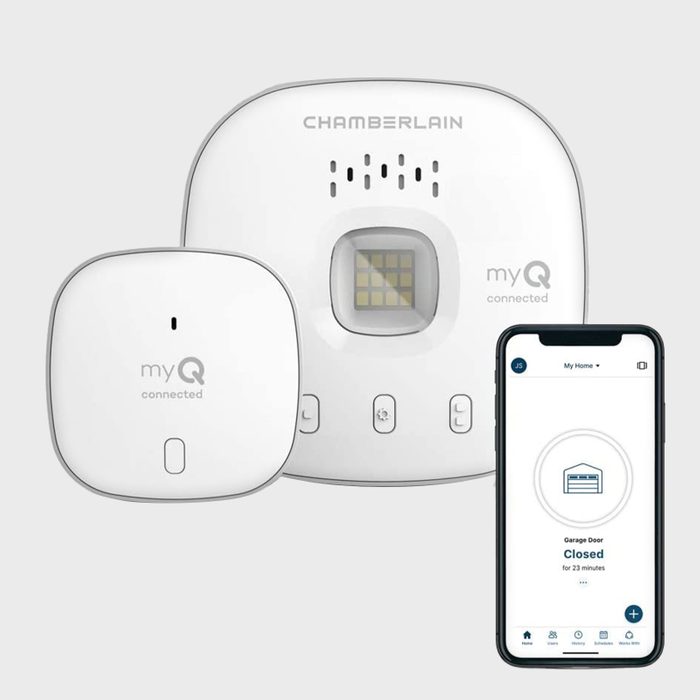 A white smart garage door controller and sensor connect to a smartphone displaying the door's status as closed. The background is plain gray.