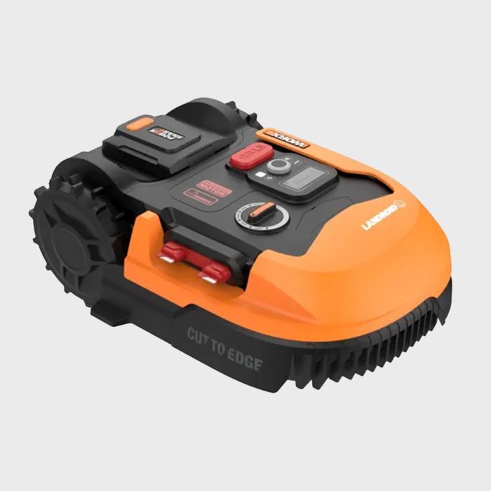 A robotic lawn mower with an orange and black design navigates grass, featuring buttons and a display for control, situated on a neutral background.