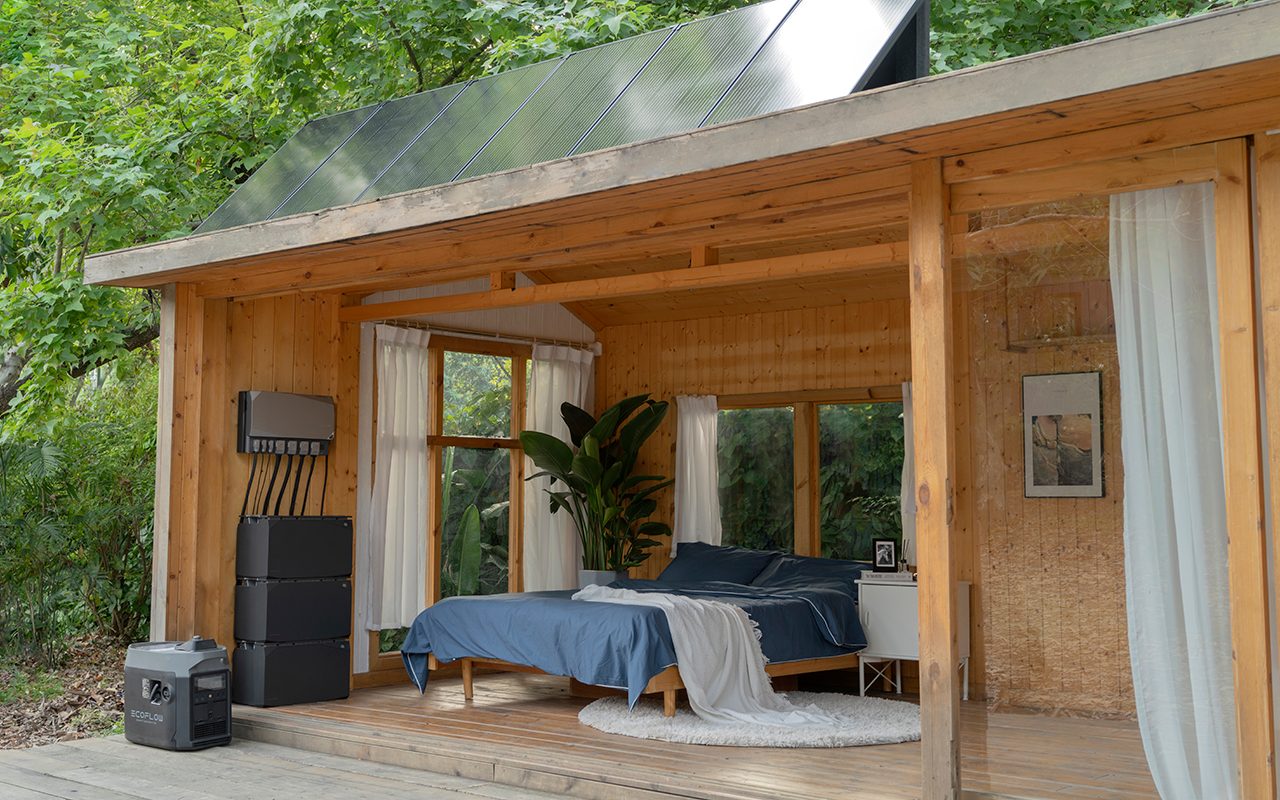A compact wooden bedroom features a bed with blue linens, standing near windows and plants, surrounded by greenery and natural light, with solar panels overhead.