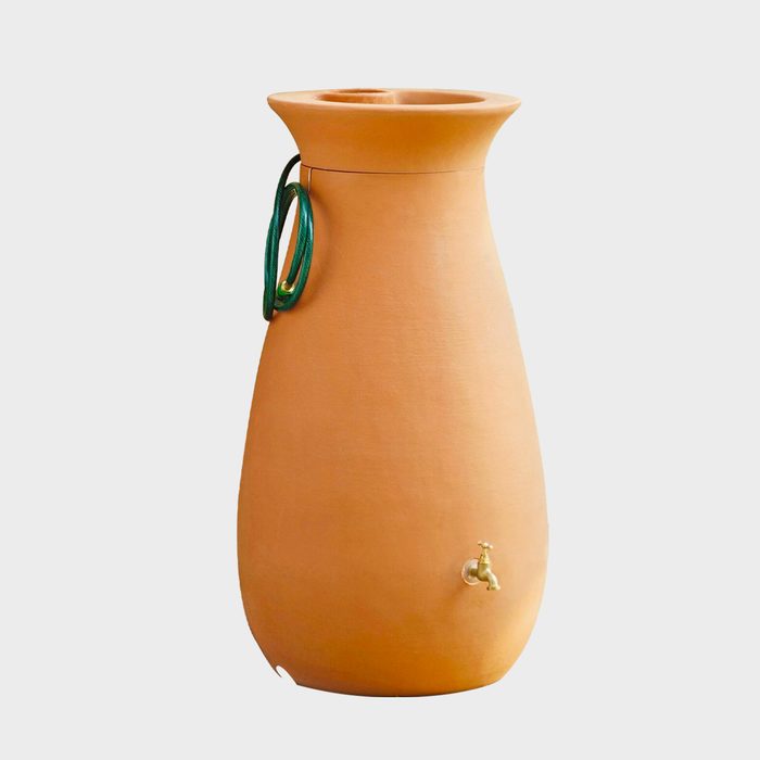 A large clay water jug stands upright, featuring a green handle and a small tap near the bottom for dispensing water.