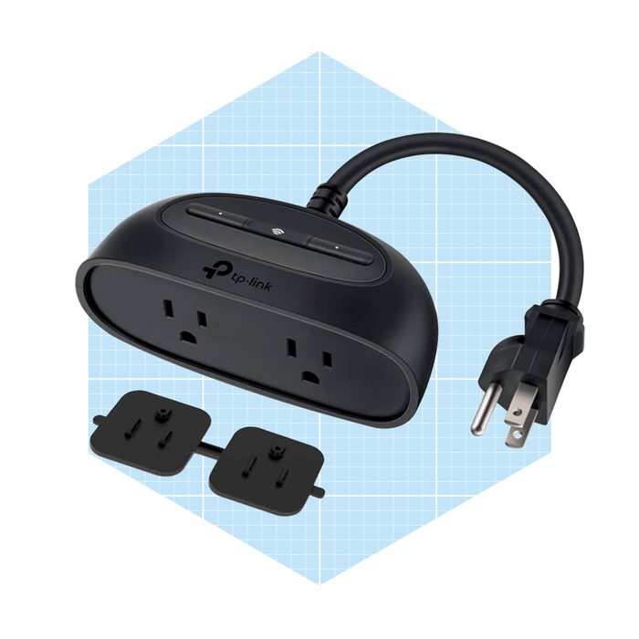A black power strip features two sockets and a connected plug, with buttons on top. It is set against a light blue grid background.