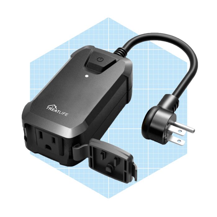 A black smart plug sits on a light grid background, with a power button on top and an electrical plug connected to it.