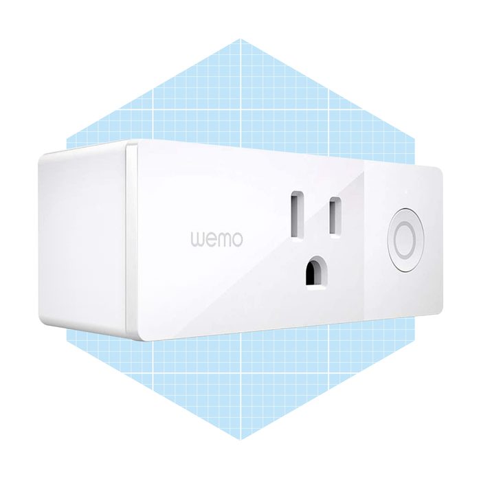 A white smart plug is displayed, designed to control devices remotely, set against a light blue grid background, indicating a modern, home technology context.