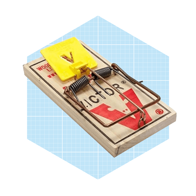 A wooden mouse trap with a yellow trigger is set, designed to capture rodents, placed against a light blue geometric background.