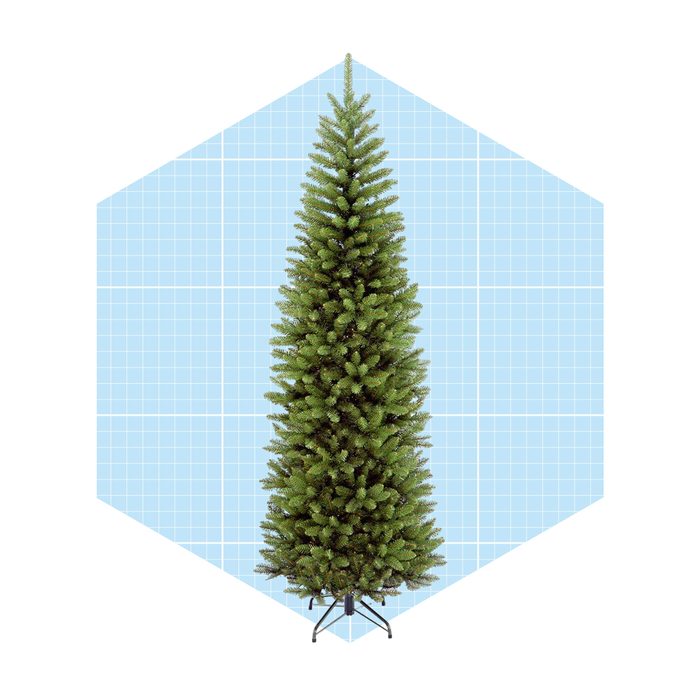 A green artificial Christmas tree stands upright on a black base, set against a light blue grid-patterned background.