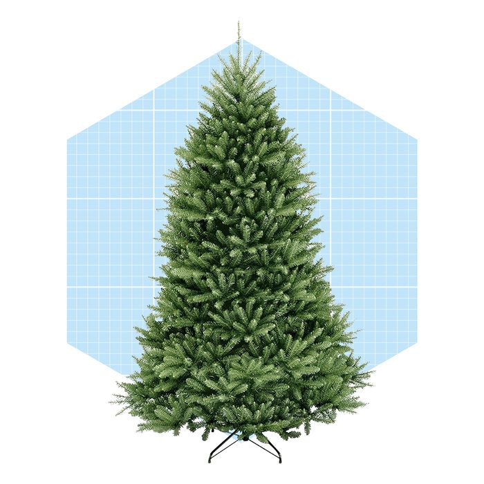 A lush green artificial Christmas tree stands upright on a black base, with a light blue grid background providing a measurement context.