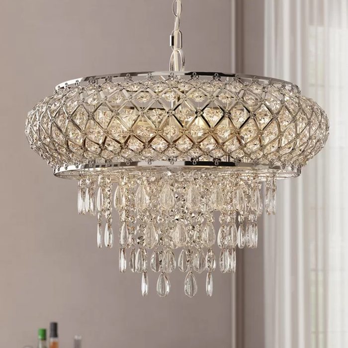 A crystal chandelier hangs from the ceiling, illuminating the space below with a sparkling glow, surrounded by soft natural light from nearby windows.