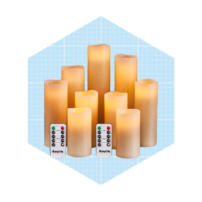 Candles emit a soft glow, arranged in a cluster with remote controls beside them, set against a light blue grid background.