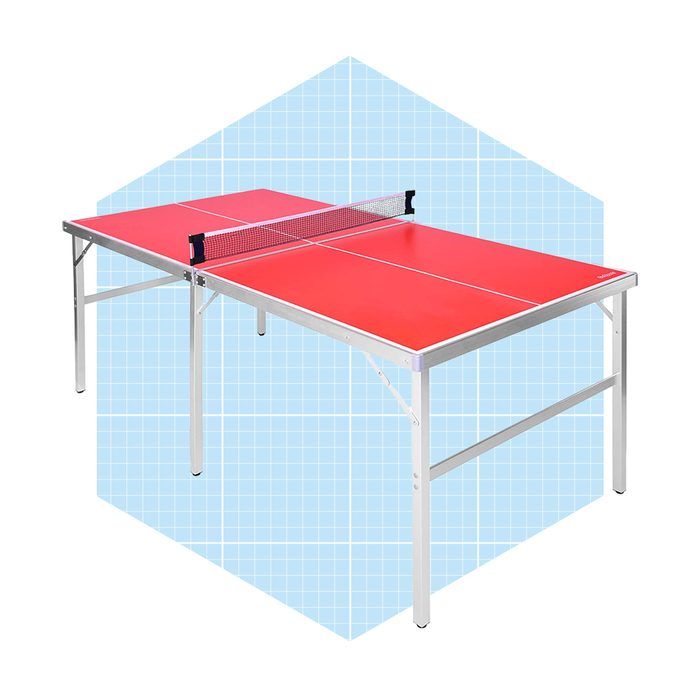 A red table tennis table stands on silver legs, featuring a net across the middle, set against a light blue grid background.