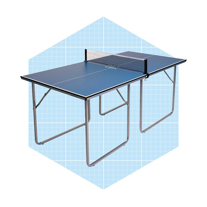 A blue ping pong table sits with a net in the middle, supported by folding metal legs against a light blue grid background.