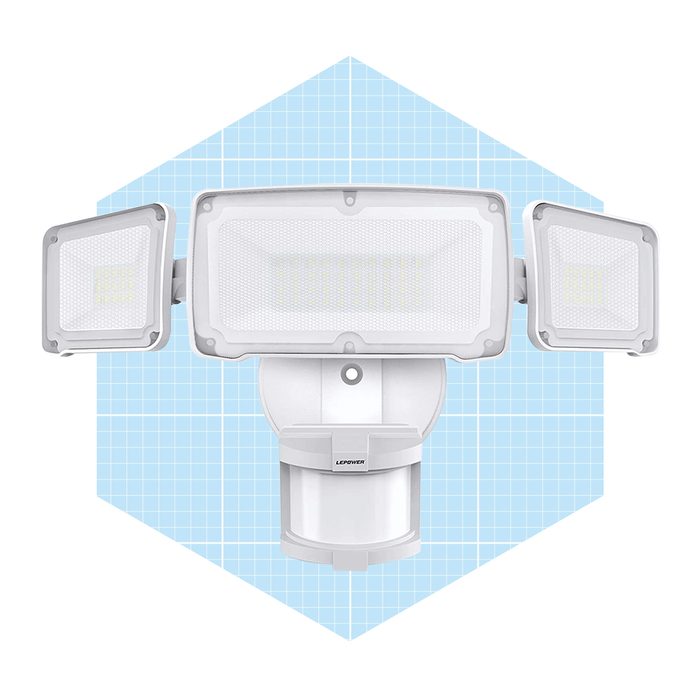 A motion sensor floodlight features three adjustable light panels, installed on a base with a sensor, against a light blue grid background.