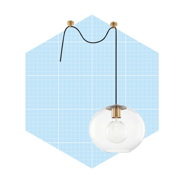 A pendant light hangs from a ceiling, illuminated by a bulb, against a light blue, grid-patterned background.