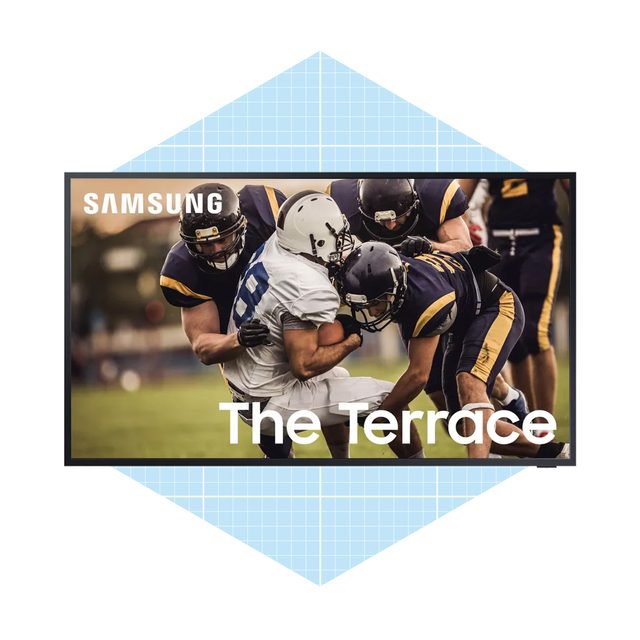A football player in a white uniform is being tackled by two opponents in dark uniforms, captured on a television screen with the text 