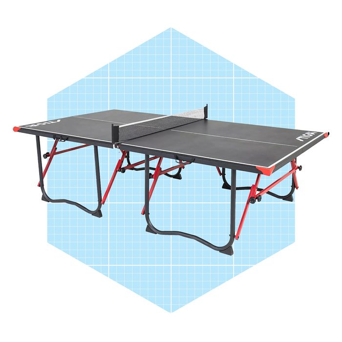 A folding ping pong table with a net is positioned on red legs, set against a light blue grid background.