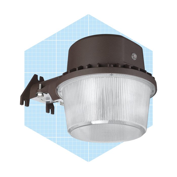 A ceiling-mounted light fixture illuminates surrounding areas. It features a clear, ribbed glass cover and a brown, rounded housing against a light blue grid background.