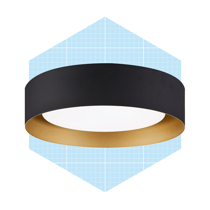A circular ceiling light, featuring a black exterior and golden interior, hangs against a light blue, grid-patterned background.