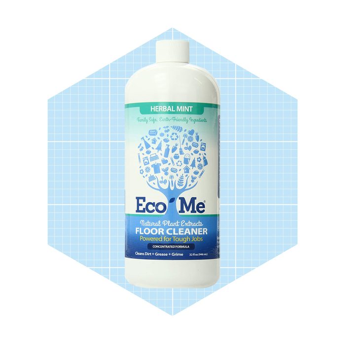 A bottle of Eco Me floor cleaner is presented upright, featuring a mint herbal scent label, against a light blue grid background.