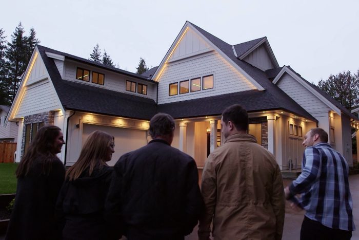 a group of people standing outside looking at the exterior of a house