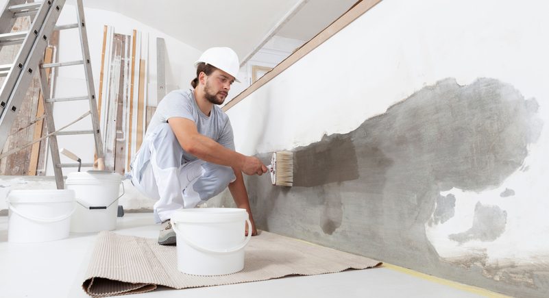 Construction Worker restores wall and paints in a home