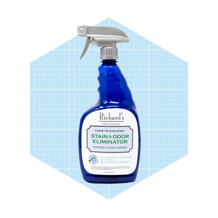 A blue spray bottle contains a stain and odor eliminator for carpets and upholstery, displayed against a light blue grid background.