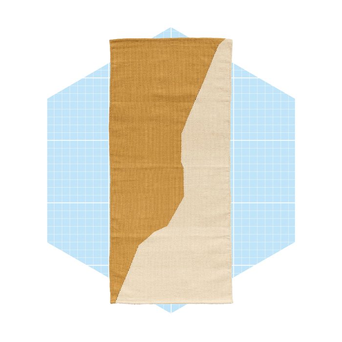 A rectangular fabric displays two colors, brown and cream, split diagonally. It's set against a light blue, grid-patterned background for contrast.