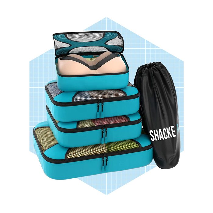 Stacked blue packing cubes and a black drawstring bag labeled 