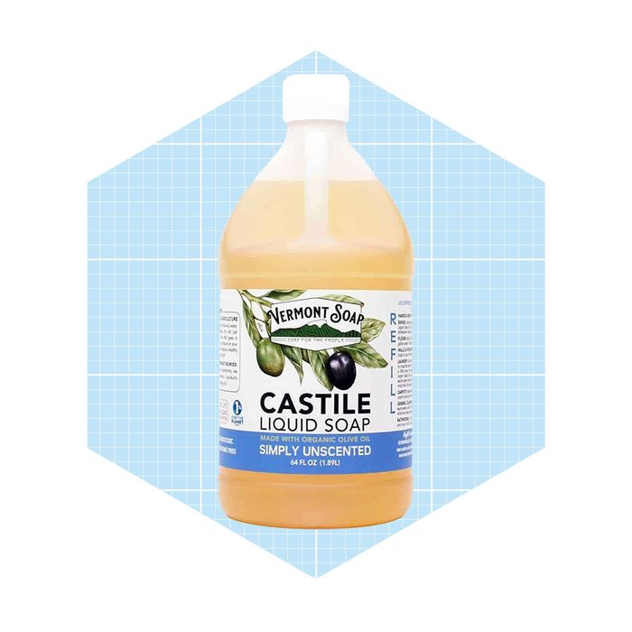 A clear plastic bottle of unscented liquid soap rests on a light blue grid-patterned background, showcasing its label with product information and branding.