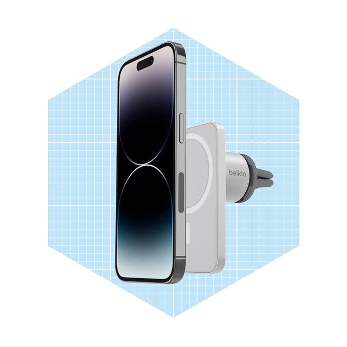 A smartphone is attached to a magnetic car charger, displaying a sleek design against a light blue grid background.