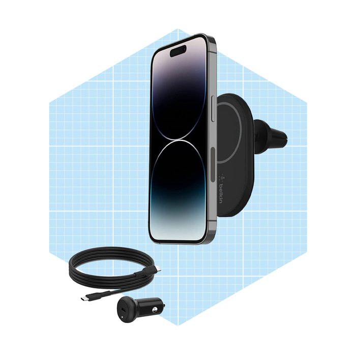 A smartphone is mounted on a car vent holder, charging cable and adapter are displayed nearby, set against a light blue geometric background.