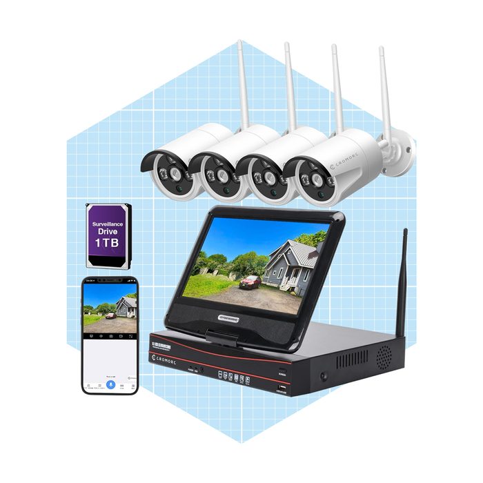 Four security cameras are mounted on a surface, connected to a monitor and a surveillance drive, displaying a house's exterior for monitoring purposes.