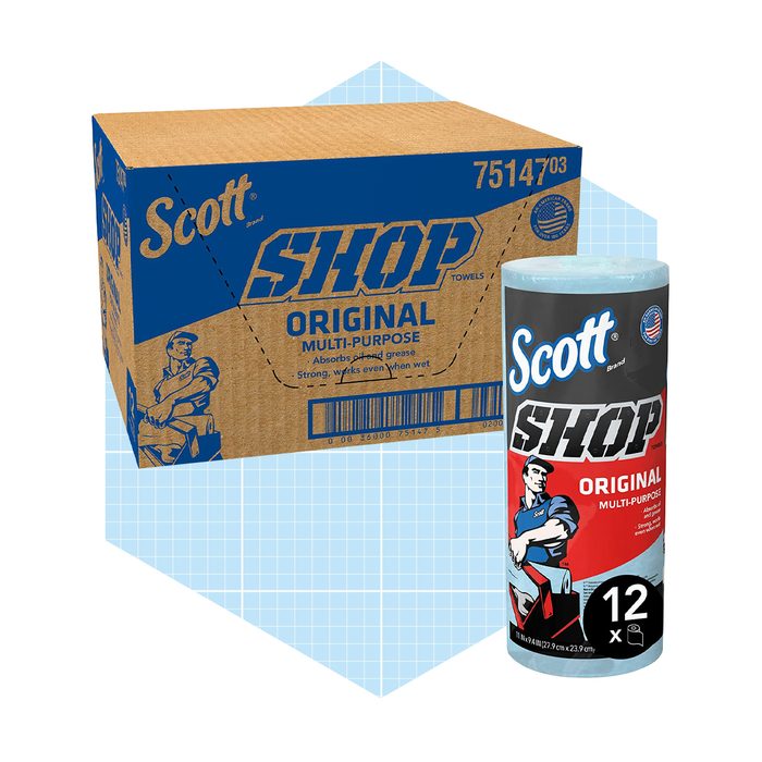 A roll of Scott Shop towels stands beside a cardboard box displaying the same product, emphasizing its multi-purpose, absorbent qualities for various cleaning tasks.