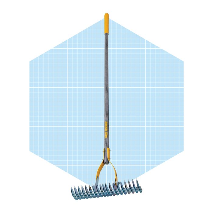 A metal rake with a long handle stands upright against a light blue grid background, designed for gardening or landscaping tasks.