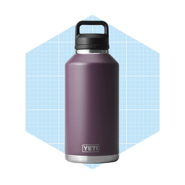 A purple insulated water bottle stands upright on a light blue grid-patterned background, showcasing a sturdy body and a black handle.