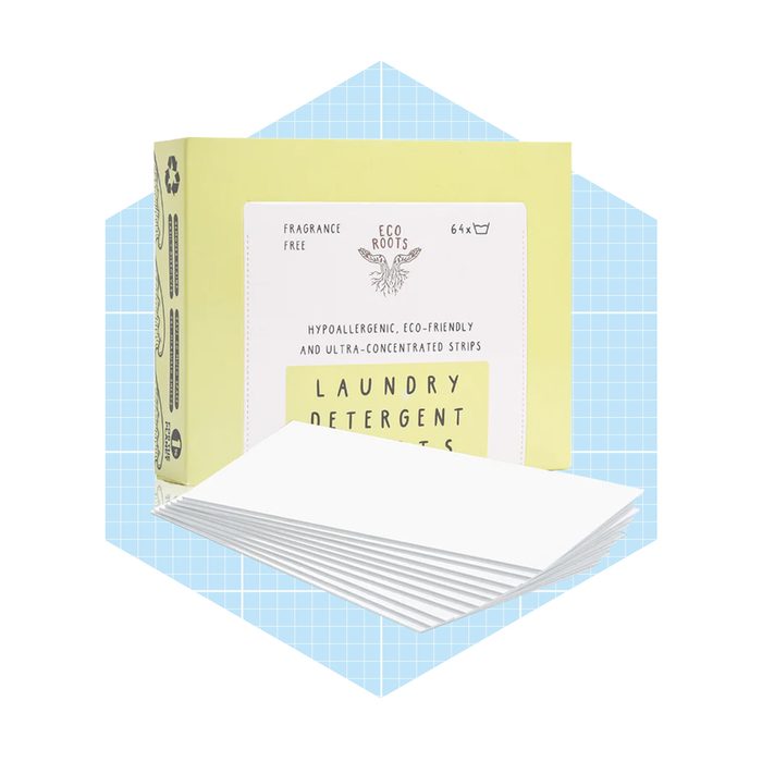 A box of eco-friendly laundry detergent strips is displayed, with several strips fanned out in front, set against a light blue grid background.