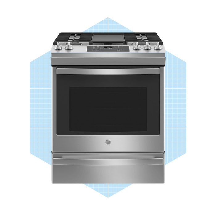 A stainless steel oven features a glass window, knobs, and control panel. It is displayed on a light blue geometric background, suggesting a modern kitchen context.