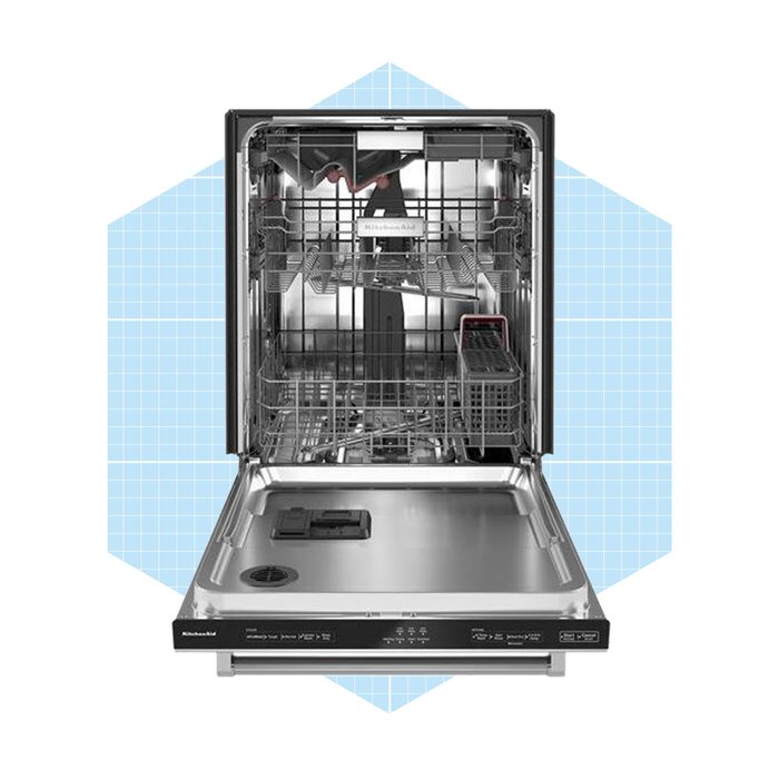 A stainless steel dishwasher stands open, revealing empty racks and a utensil basket, set against a light blue geometric background.