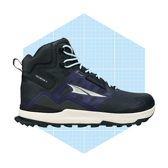 A hiking shoe stands upright, featuring a black and purple design with light blue laces, set against a light blue geometric background.