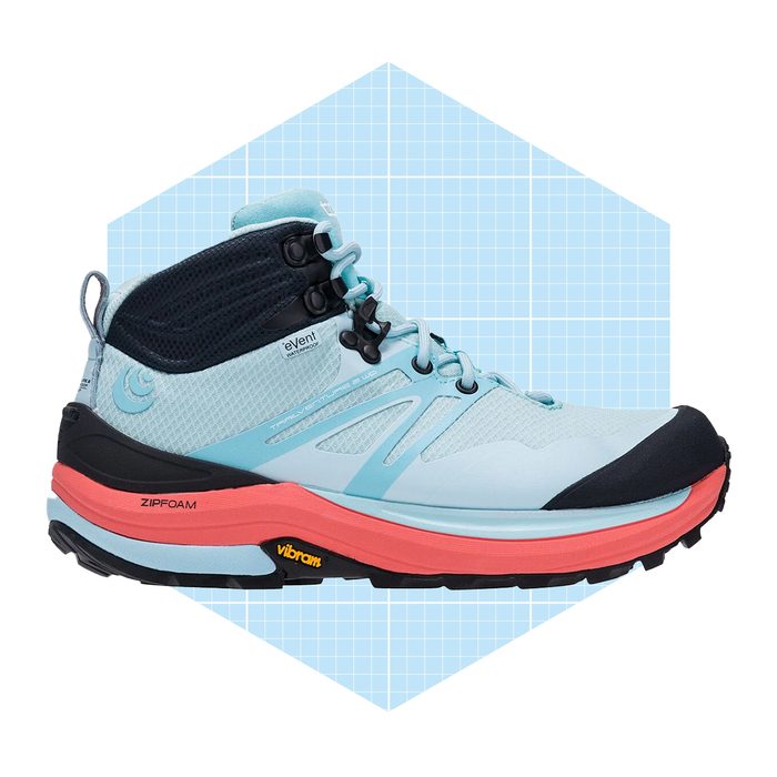 A light blue hiking shoe stands upright, showcasing its rugged design and vibrant sole, against a soft blue grid background.