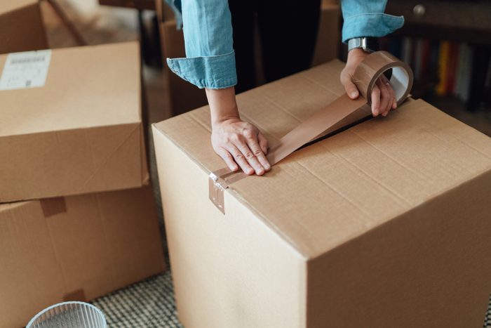 Close-up of female hand packing cardboard boxes